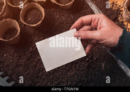 Gardener holding blank business card mock up au-dessus de l'agriculture biologique et de l'équipement de jardinage Banque D'Images