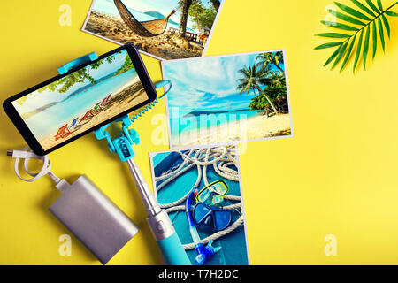Mise à plat avec un monopode et smartphone photos sur un fond jaune. Summer travel concept Banque D'Images
