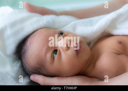 Asian baby boy smiling et se sentir heureux après la prise de bain. mère sèche et frotte son bébé nouveau-né et cheveux tête avec une serviette après la douche. f