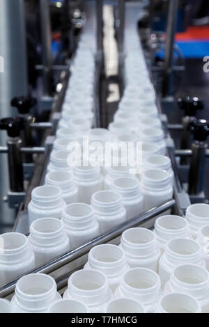 Bouteille en plastique blanc sur la ligne de production de la machine de remplissage à convoyeur à l'usine. focus sélectif. Banque D'Images