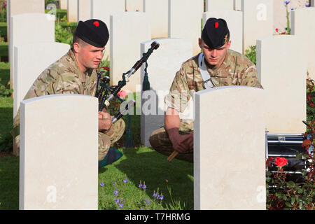 Un Piper et un batteur des Black Watch en l'honneur des soldats tués à la Deuxième Guerre mondiale, le cimetière de guerre de Ranville en Normandie, France Banque D'Images