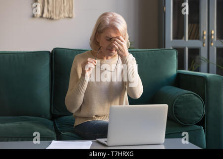 Femme mature aux cheveux gris le massage du nez, la fatigue visuelle concept Banque D'Images