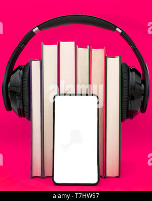 Livres audio concept. Mettre les écouteurs sur livre sur fond violet rose. Téléphone intelligent. Téléphone mobile.vue avant copy space Banque D'Images