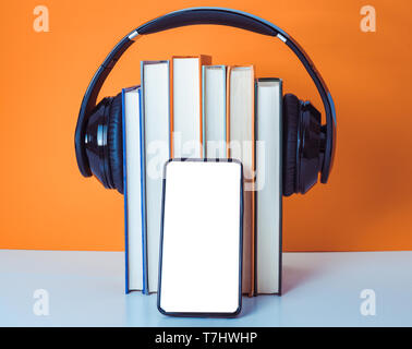 Livres audio concept. Mettre les écouteurs sur livre sur fond blanc et orange. Téléphone intelligent. Téléphone mobile.vue avant copy space Banque D'Images