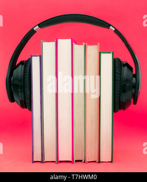 Livres audio concept. Mettre les écouteurs sur livre sur fond violet rose. Banque D'Images