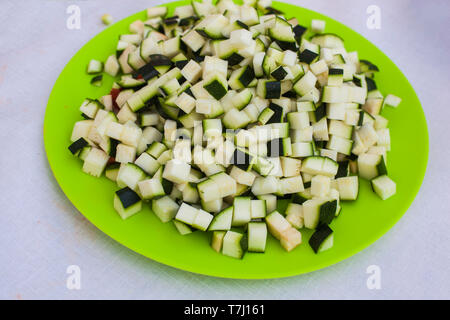 Une plaque verte pleine de matières premières courgettes en dés vert prêt à obtenir dans la casserole. Banque D'Images