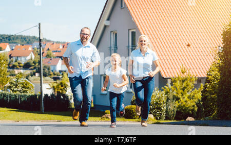 Famille heureuse courir devant leur nouvelle maison Banque D'Images