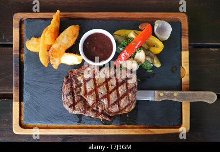Vue de dessus du steak ribeye grillé avec sauce au vin rouge servi chaud sur la plaque en pierre Banque D'Images