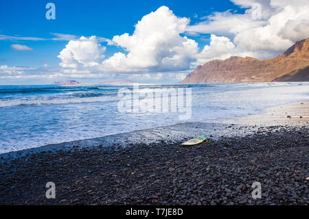 Plage volcanique de Famara avec un surf en attente d'une vague en Lanzarote shores Banque D'Images