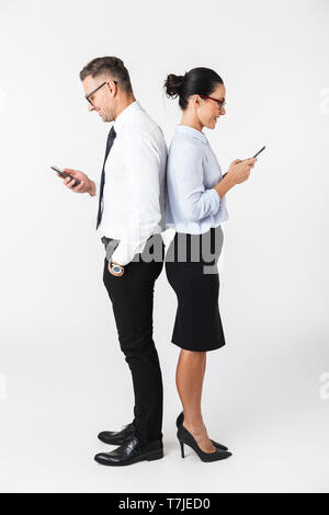 Toute la longueur d'un couple portant des vêtements formels collègues isolés sur fond blanc, à l'aide de mobile phone Banque D'Images