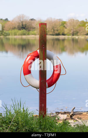 Rouge et blanc un épargnant de vie anneau rouge se bloque sur un post sur les rives d'un réservoir. Corde Orange tombe autour de l'anneau. Banque D'Images