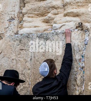 L'homme juif prie à côté d'une fissure remplie de lettres écrites contenant la prière au Mur des lamentations à Jérusalem. Israël Banque D'Images