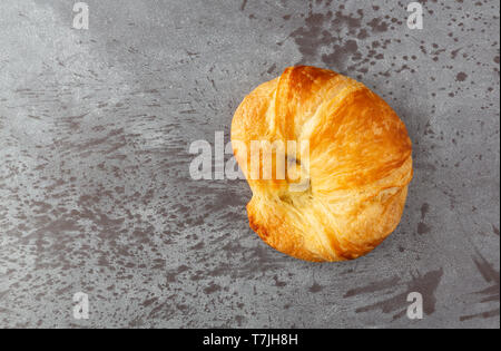 Vue de dessus d'un croissant fraîchement cuits sur un fond gris éclairés par la lumière naturelle. Banque D'Images