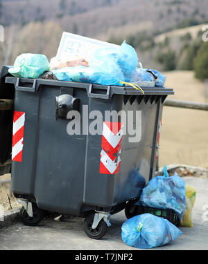 Petite poubelle noire et beaucoup de sacs à déchets sur la rue de la ville de montagne Banque D'Images