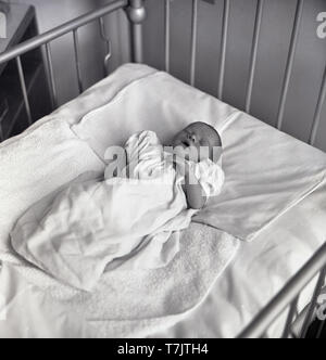 Années 1960, historique, dans un hôpital, un nouveau-né endormi dans un lit en métal, England, UK. Banque D'Images