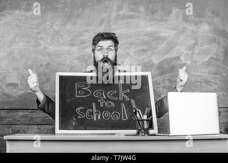 Début de nouvelle année scolaire en septembre. Enseignant accueille de nouveaux élèves à entrer dans l'établissement d'enseignement. Enseignant ou directeur d'école accueille avec tableau noir inscription retour à l'école. Bienvenue à nouveau. Banque D'Images