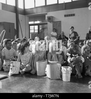 Années 1960, historiques, excité les jeunes enfants de l'école dans la salle d'école leur main pour poser une question, England, UK. Banque D'Images