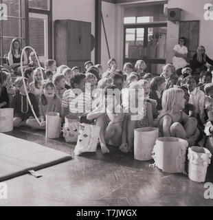 Années 1960, historiques, excité les jeunes écoliers assis sur le plancher d'une salle d'école, England, UK. Banque D'Images
