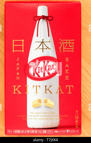 Extérieur de la boîte en carton rouge souvenir de mini barres Kitkat à saveur de saké au chocolat blanc japonais, avec une bouteille de saki blanc sur la couverture. Banque D'Images