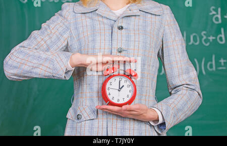 La discipline scolaire concept. L'annexe et de régime. Réveil de femmes de près. Les enseignants des attributs. Réveil dans les mains de l'enseignant ou éducateur classe tableau arrière-plan. Banque D'Images