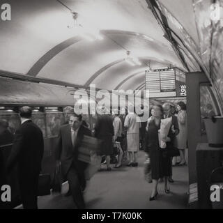 60, tableau historique du métro de Londres, un train de tube sur la ligne Bakerloo Line à une plate-forme, les gens monter et descendre du train, Londres, Angleterre, Royaume-Uni. Ouvert en 1906, la ligne Bakerloo line s'étend du nord-ouest de Londres à Londres du sud via l'ouest de la ville. Banque D'Images