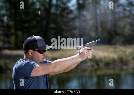 Un homme avec un pistolet de tir le shell éjecté en l'air. Banque D'Images