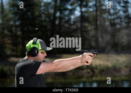 Un homme avec un pistolet de tir le shell éjecté en l'air. Banque D'Images