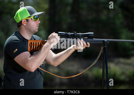 Un homme armé d'un fusil à verrou avec le shell éjecté en l'air. Banque D'Images