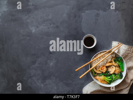 Brochettes de poulet, brocoli et faire sauter les champignons dans un bol avec du riz blanc sur fond de béton gris. La cuisine asiatique. Vue de dessus avec l'espace pour le texte. Banque D'Images