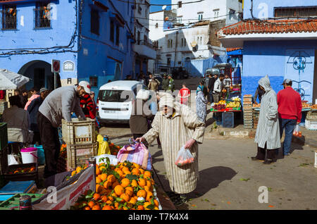 Chefchaouen, Maroc : un homme portant une djellaba marocaine boutiques pour les fruits et légumes sur la place Bab Suk place du marché, dans le bleu délavé-med Banque D'Images