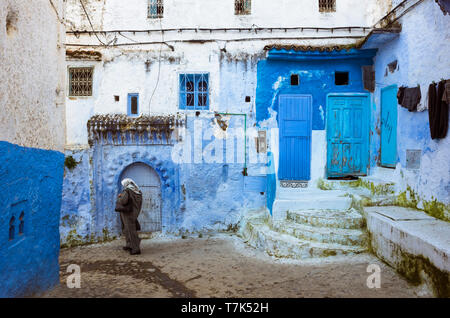 Chefchaouen, Maroc : Une marocaine passe devant les bâtiments traditionnels blanchis à bleu dans la médina vieille ville. Banque D'Images