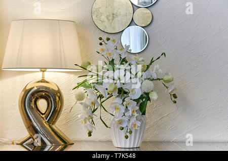 Chambre d'intérieur vase lampe avec des fleurs et un miroir décoratif sur une lumière Banque D'Images