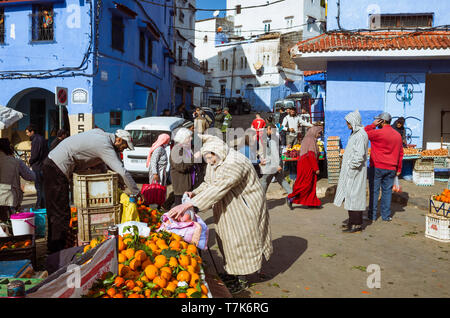 Chefchaouen, Maroc : un homme portant une djellaba marocaine boutiques pour les fruits et légumes sur la place Bab Suk place du marché, dans le bleu délavé-med Banque D'Images