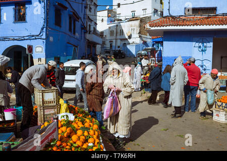 Chefchaouen, Maroc : un homme portant une djellaba marocaine boutiques pour les fruits et légumes sur la place Bab Suk place du marché, dans le bleu délavé-med Banque D'Images