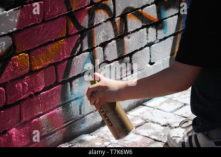 La photo d'un jeune garçon sur tippy-orteils de peindre sur un mur légal à Cambridge, MA (le 17 avril 2019) Banque D'Images