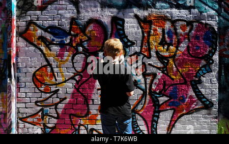 La photo d'un jeune garçon sur tippy-orteils de peindre sur un mur légal à Cambridge, MA (le 17 avril 2019) Banque D'Images