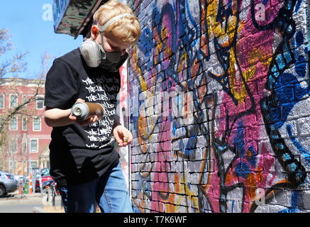 La photo d'un jeune garçon sur tippy-orteils de peindre sur un mur légal à Cambridge, MA (le 17 avril 2019) Banque D'Images