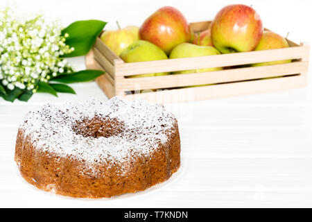 Gâteau bundt Apple sur table en bois blanc avec pommes et bouquet de printemps. Certains soft focus Banque D'Images