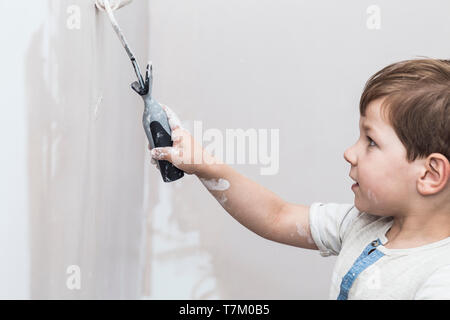 3 ans adorable petit garçon avec rouleau à peindre à la main. Un enfant à un concept corvées Maison Banque D'Images