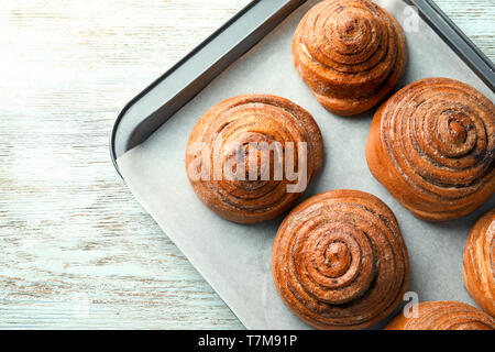 La plaque de cuisson avec des brioches à la cannelle sucrée sur table Banque D'Images