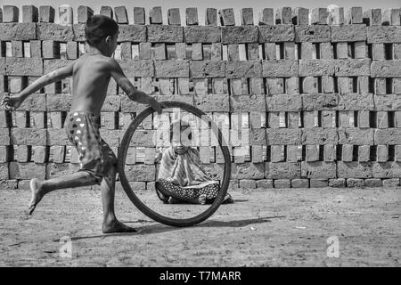 Kolkata : en date du 04/02/2018, un village près de brick kilin , les gens vivent dans la boue des maisons, les enfants jouent à courir avec les pieds d'ours provenant de pneus, les petites filles tr Banque D'Images