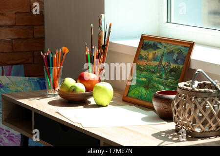 Table avec les outils de peinture, photo et savoureuses pommes en atelier d'artiste Banque D'Images