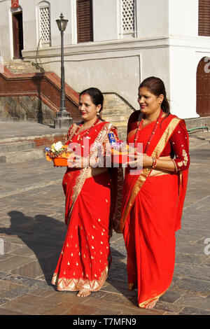 Les femmes en saris colorés de rouge et d'or hold offrandes religieuses au temple hindou de Pashupatinath, Vallée de Katmandou, Népal Banque D'Images