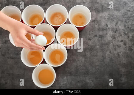 Woman holding white ball plus de tasses organisé pour jouer au Beer Pong Banque D'Images