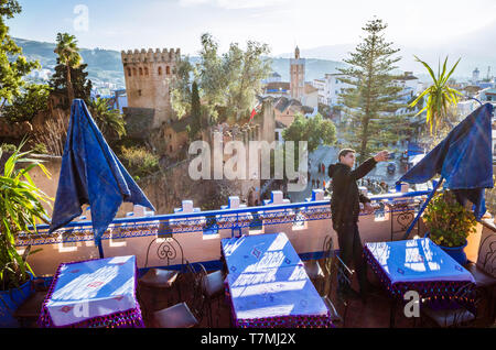 Chefchaouen, Maroc : un homme prend une à selfies le toit de l'Hôtel Aladin avec la Kasbah forteresse en arrière-plan. Banque D'Images