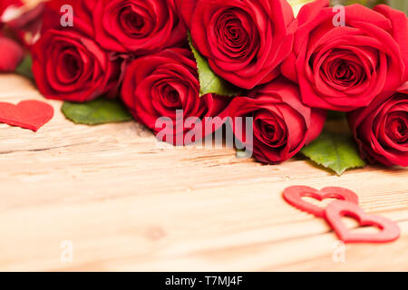 Roses rouges avec des coeurs sur table en bois Banque D'Images