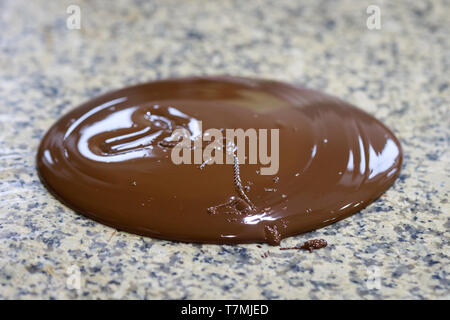 Le chocolat tempéré liquide coulé sur une table en granit. Close-up Banque D'Images