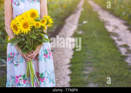 Girl holding un énorme bouquet de tournesols dans leurs mains Banque D'Images