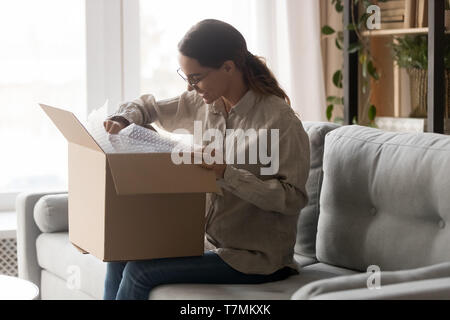 Femme grande boîte de carton sur tours déballer les marchandises livrées Banque D'Images