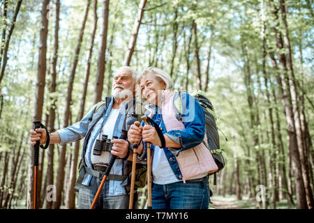 Beau couple randonnées avec sacs à dos et bâtons de trekking dans la forêt. Concept de vie active à la retraite Banque D'Images